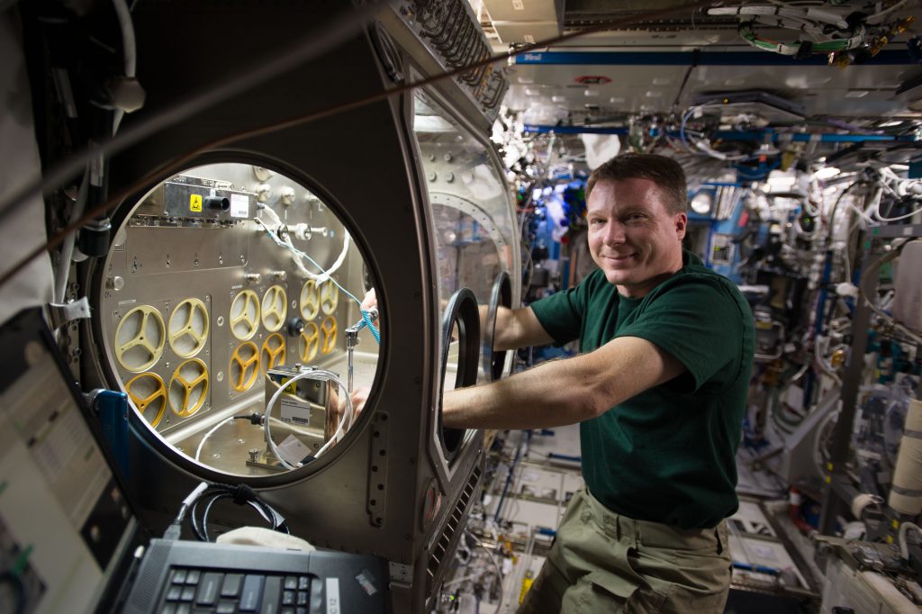 An ISS crew member works on the Microgravity Glove Box
